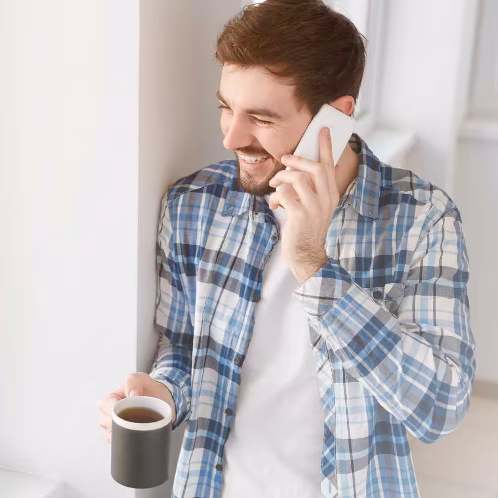 Jeune expert-comptable souriant au téléphone avec un café, illustrant l’accompagnement personnalisé en création d’entreprise à Vertou